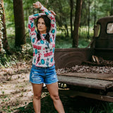 Front view of cream-colored mesh long sleeve with pink and teal western designs. Includes the word "Howdy" in pink lettering. 