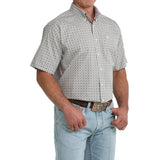 Angled view of model in Cinch Men’s Grey and White Geo Print Short Sleeve Shirt, highlighting sleeve detail, tailored silhouette, and geo print design.