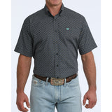 Front view of man wearing a black short sleeve shirt with turquoise geometric print standing in front of white background.