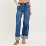 Full view of the front of the jeans, high rise waist, cuffed bottoms, and sewn seam that runs down the middle of each leg.