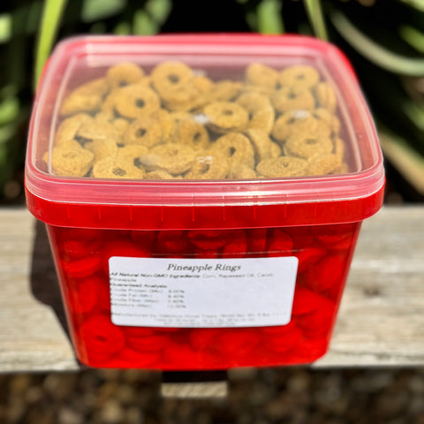 Red container filled with pineapple rings horse treats on a wooden surface
