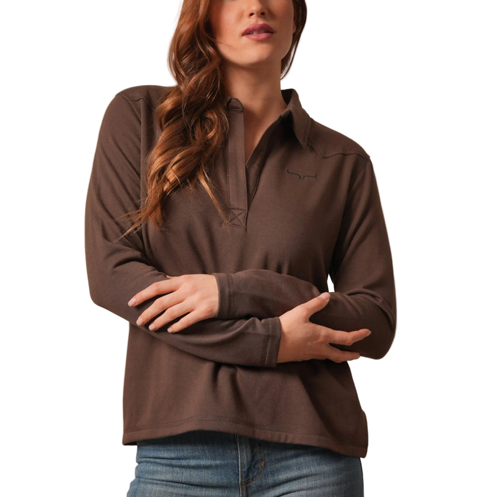 A woman wearing a brown long-sleeve collared pullover top with a partial placket and subtle longhorn chest logo.