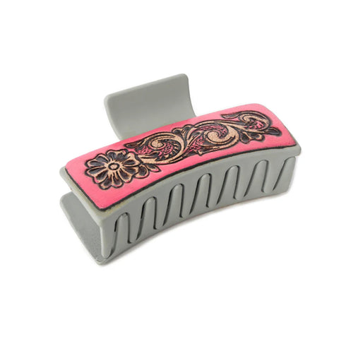 Grey plastic hair clip with pink tooled leather on the sides. 