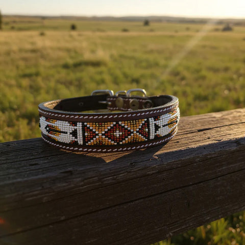 Leather dog collar with a geometric gold, brown, white, and black beaded design.