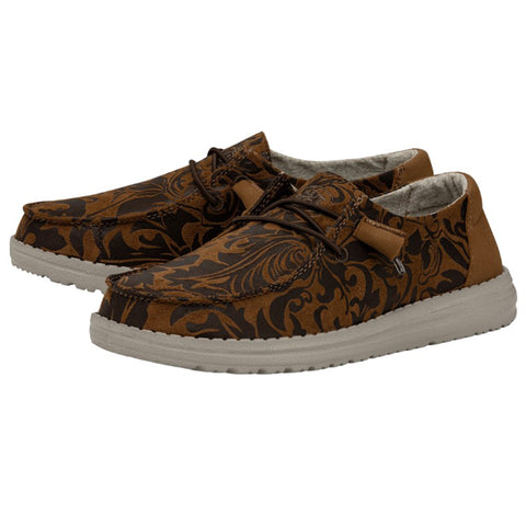 A pair of brown HEYDUDE shoes that feature a western-inspired floral design.