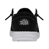 The backside view of a HEYDUDE shoe. The back of this shoe is black with a patch that contains HEYDUDE on it.