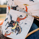 Close-up of a patterned fabric with illustrations of people on horses.