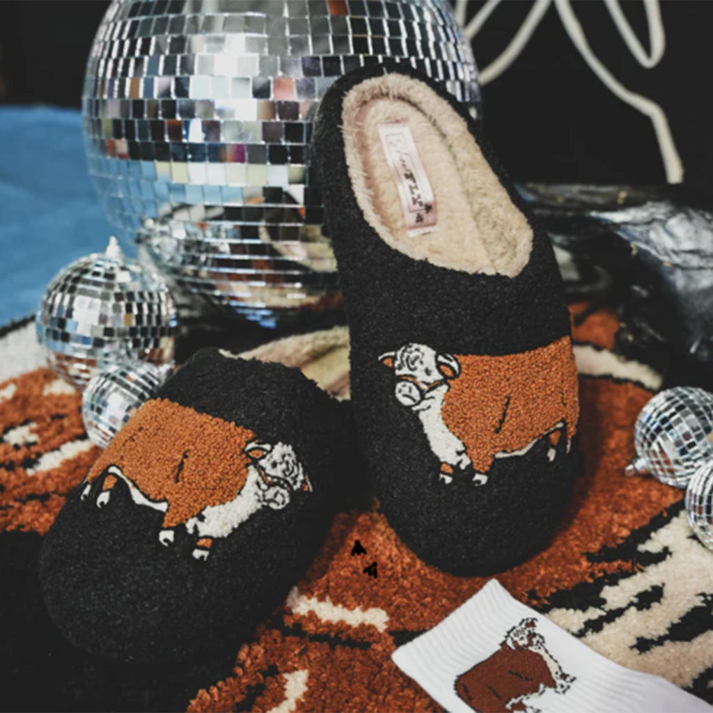 warm and fuzzy black slippers with Hereford bull on them