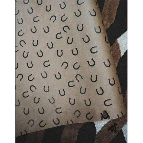 Brown kraft wrapping paper with black horseshoe pattern on a patterned background