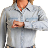 Close‑up of the model’s wrist showing the denim shirt cuff with snap closure.