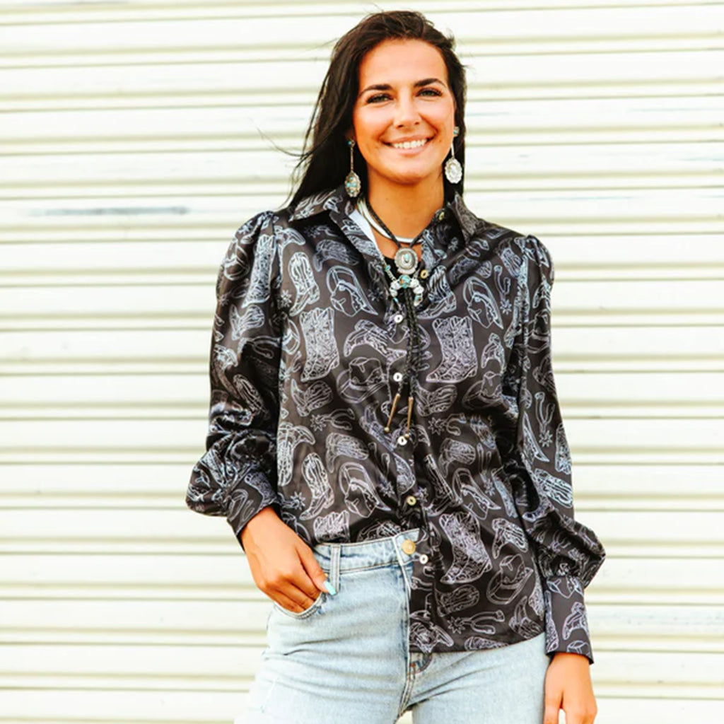 Black long sleeve satin shirt with a button closure down the middle, flowy sleeves, and white cowboy boot print. 