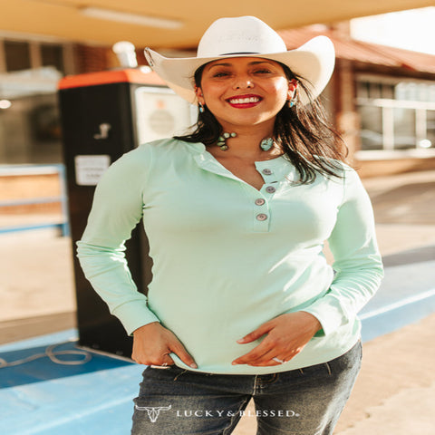 Woman wearing a mint ivory quarter-button long-sleeve shirt with a relaxed fit, styled with denim and Western-inspired accessories.