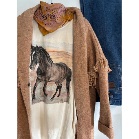 Ivory Tango Black Horse Tee hanging on a hanger, showing the bold black horse graphic on the soft ivory fabric.