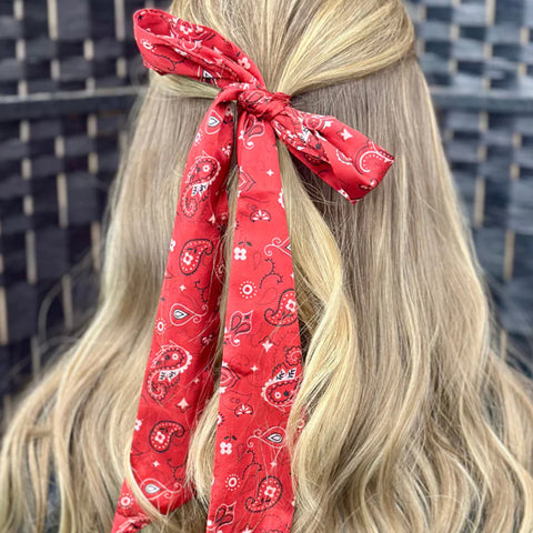 Red bandana twilly tied in a bow in models hair. 