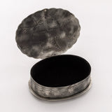 Open oval stamped box showing the velvet-lined interior for storing jewelry and small keepsakes.