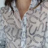 White sheer blouse with pearly white buttons and a black classic horseshoe design 