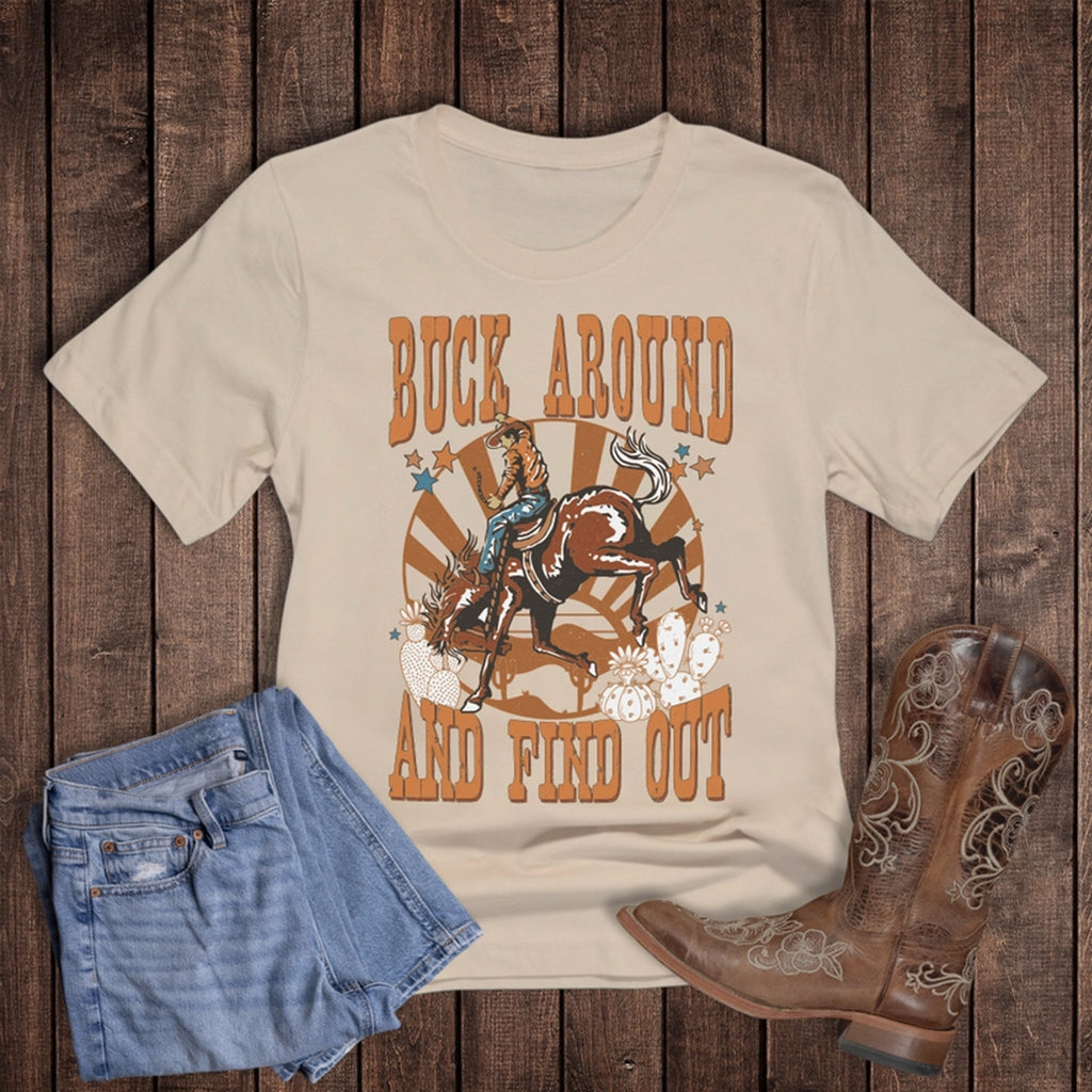 Flat lay of buck around and find out tee with jeans and boots.