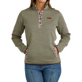 Woman wearing sage green ribbed pullover sweater with a patterned snap-placket collar and front kangaroo pockets, paired with blue jeans.