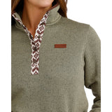 Close-up of a sage green ribbed pullover sweater featuring a stand collar, brown-and-cream geometric patterned snap placket, and a small leather chest logo patch.