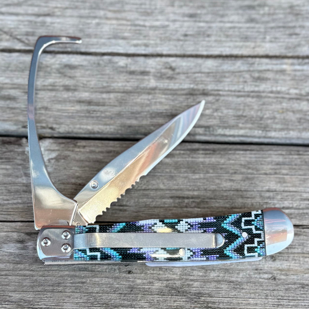 Serrated knife with hoof pick and purple, blue, white, and black bead pattern handle.