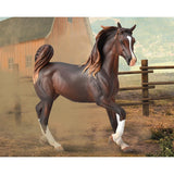 Model horse in a rustic setting with a barn