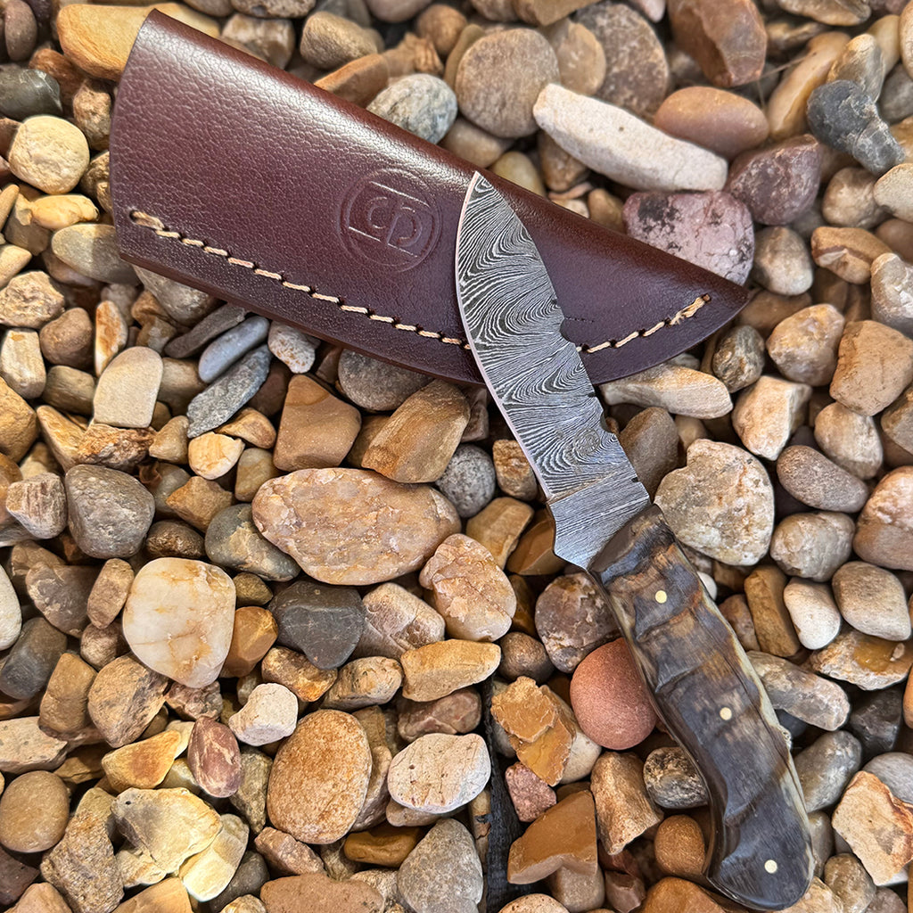 Damascus fixed blade knife with ram horn handle and leather sheath.