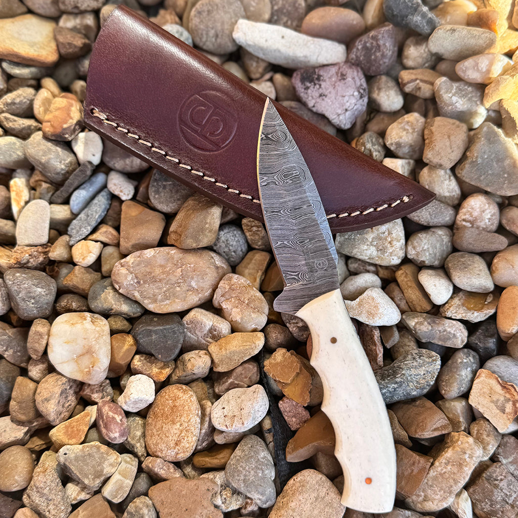 Damascus blade knife with bone handle and leather sheath.