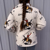 Person wearing a white quilted jacket with horse and rider designs on a gray background