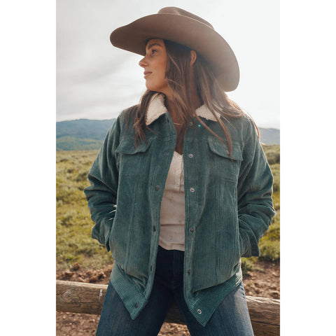 Woman wearing Sage Corduroy Berber Jacket styled with denim and hat in rustic outdoor setting