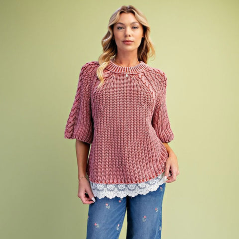 Model wearing a classic rust‑hued knit sweater with delicate lace detailing along the bottom hem.