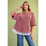Model wearing a classic rust‑hued knit sweater with delicate lace detailing along the bottom hem accenting the half sleeves.