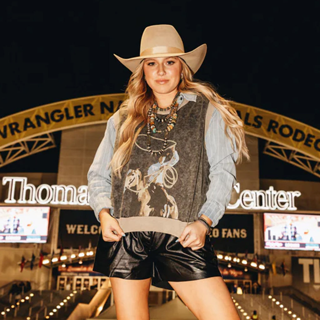Model wearing the Chocolate Swing Wide Sweater Vest featuring a cowboy swinging a rope