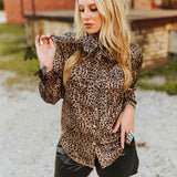 Blouse has a ribbon tie at the neckline, model is holding part of the bow.