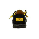 The backside view of a black HEYDUDE shoe. There is a yellow patch on the back displaying HEYDUDE's logo.