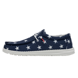 A blue shoe containing a white star pattern (by HEYDUDE) pictured from the side atop a white background.