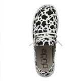 A pair of black and white cow print HEYDUDE Wendy shoes with white laces on a white background.